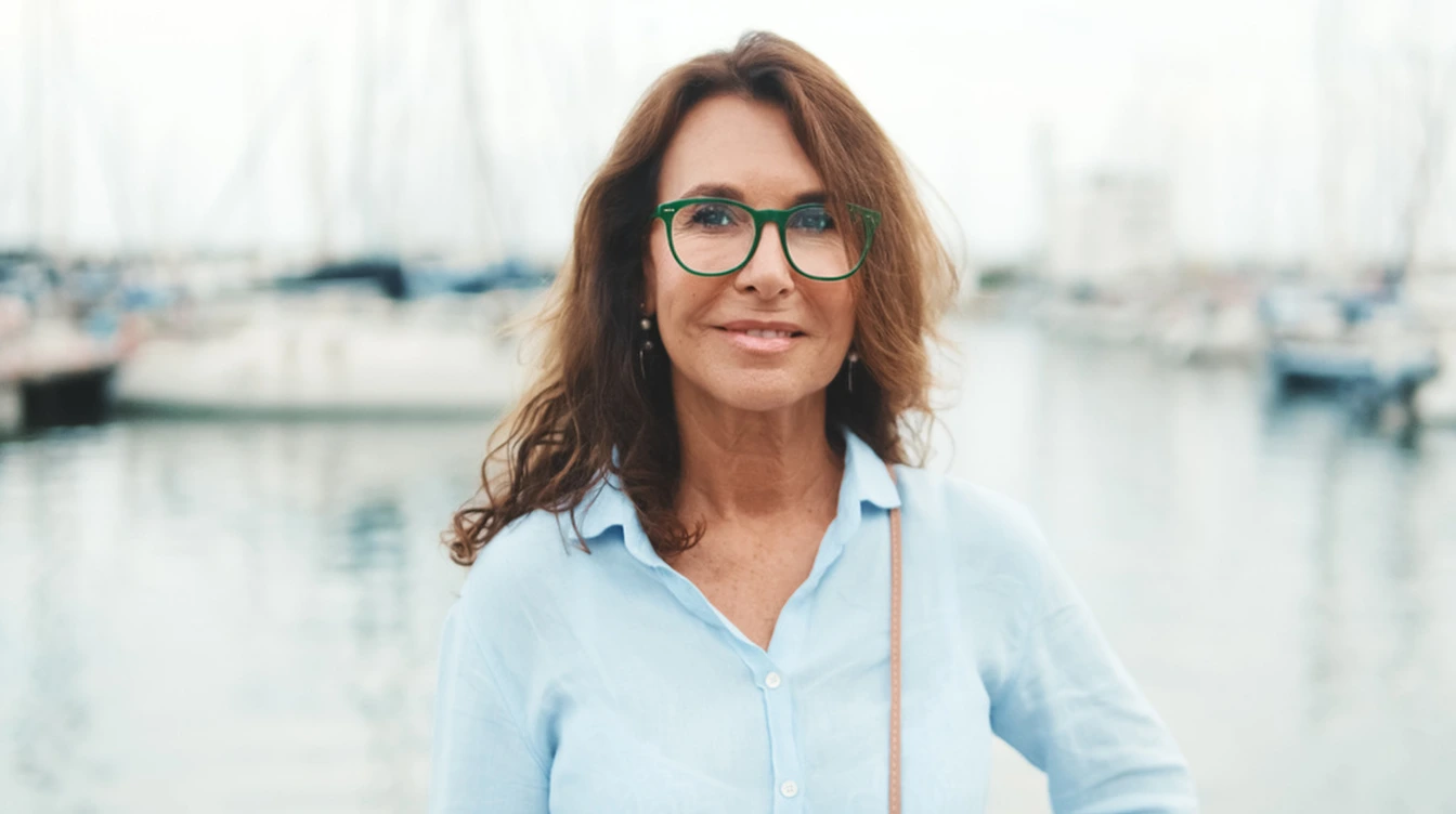 Mujer con anteojos y camisa celeste junto a un puerto