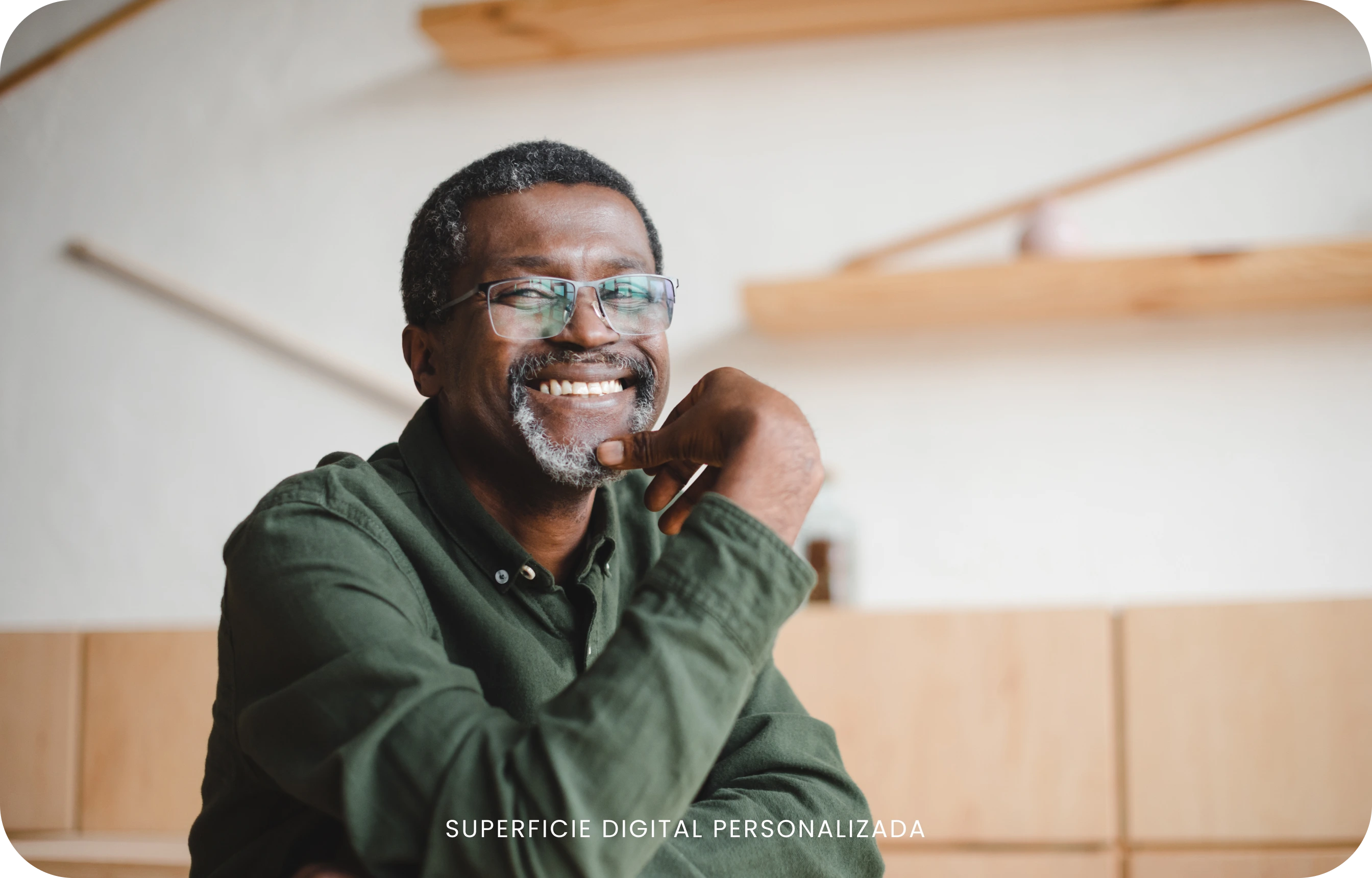 Hombre con anteojos y camisa verde sonriendo en interiores