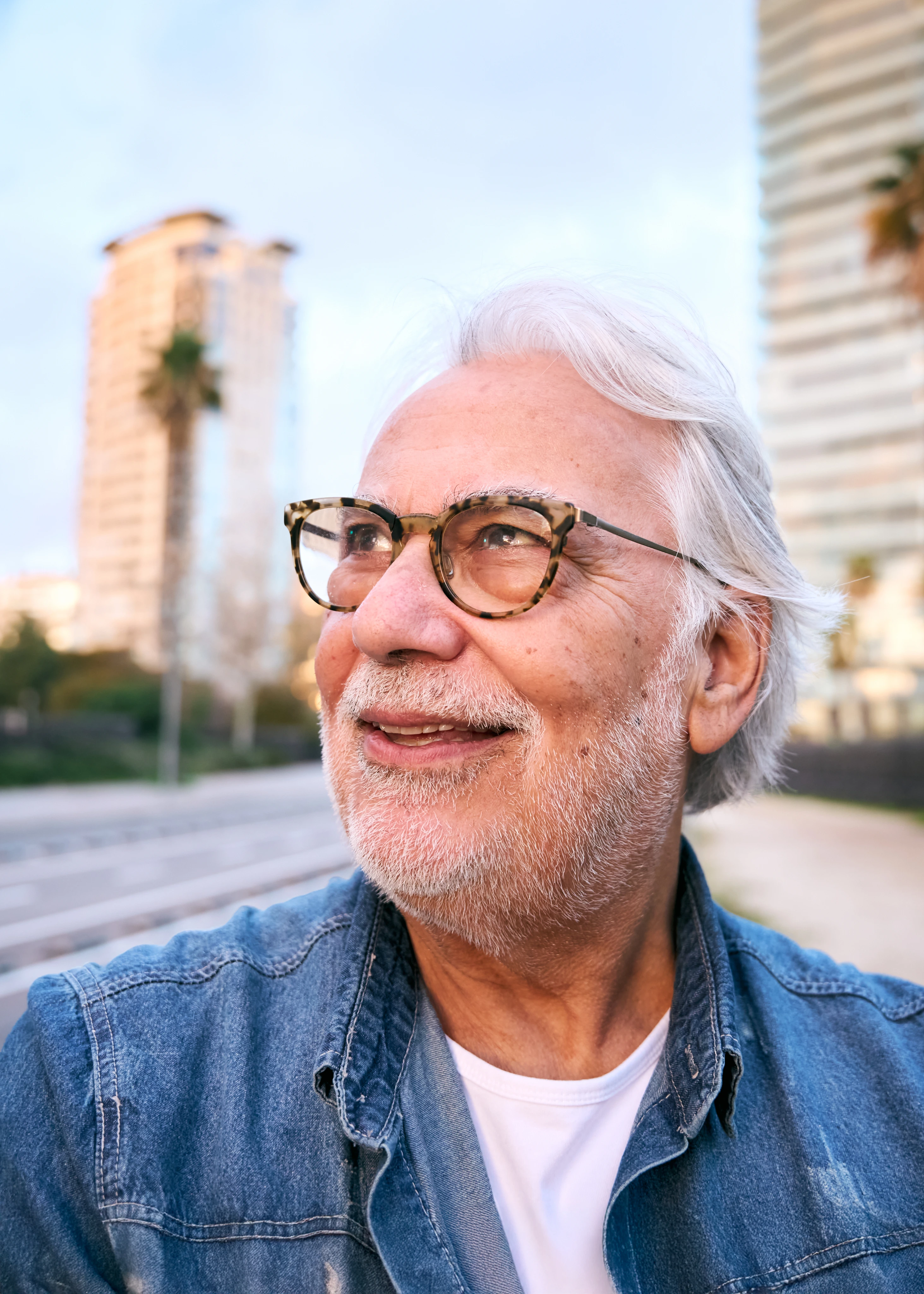 Hombre mayor con anteojos y chaqueta de jean en la ciudad