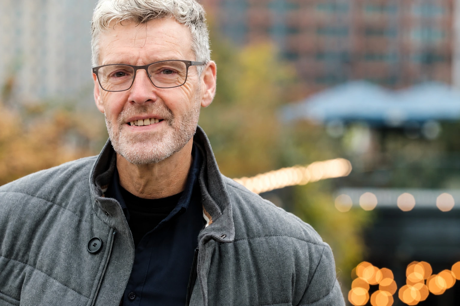 Hombre con anteojos y chaqueta gris al aire libre